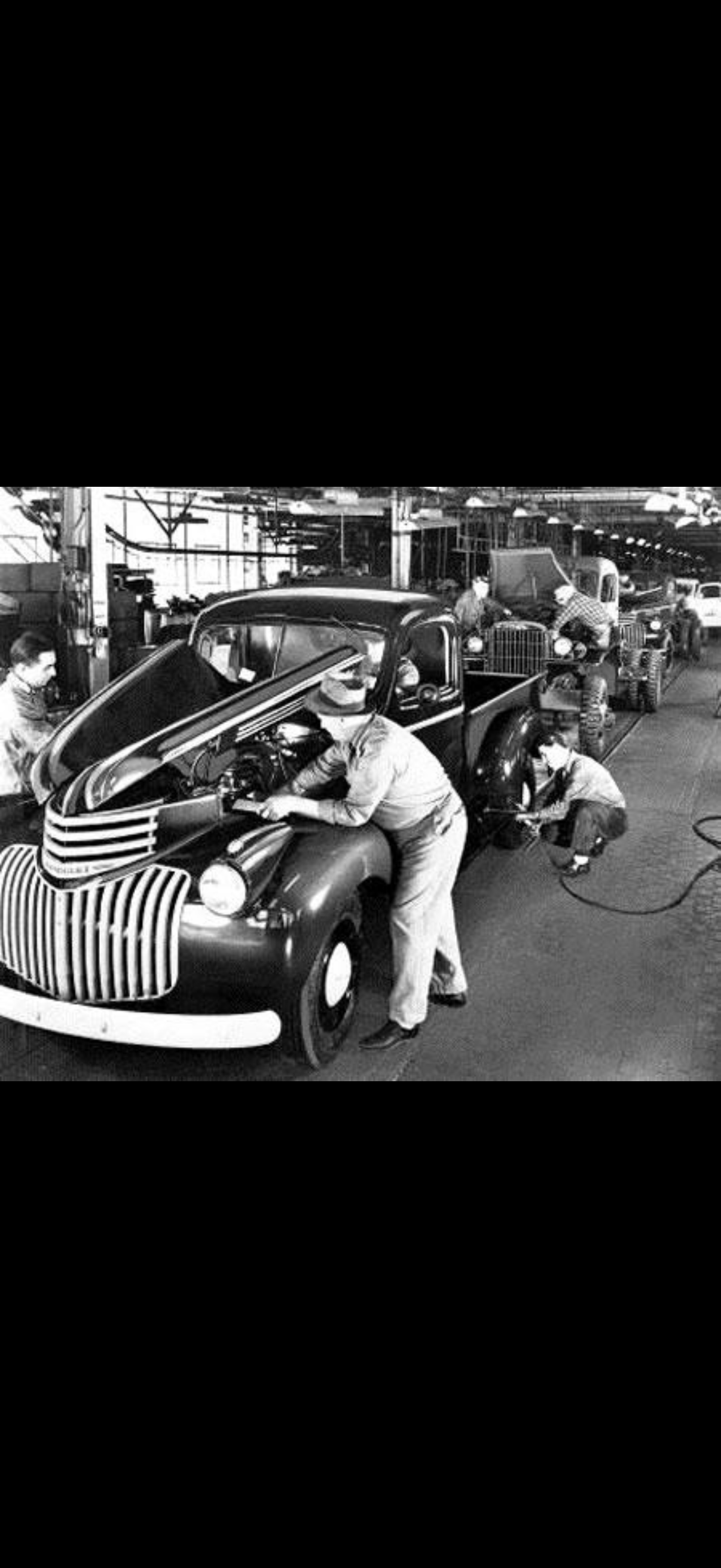 General Motors Chevrolet assembly line workers, 1940s — mechanics working on trucks on the factory floor