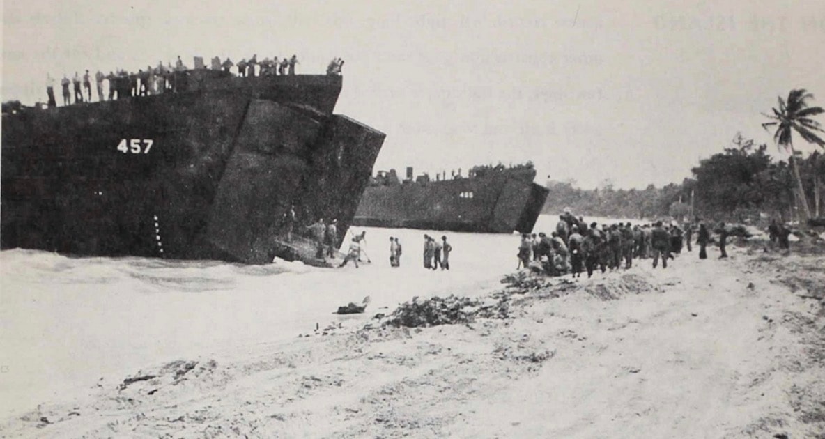 USS LST-457 — bow doors open, troops and vehicles disembarking on Pacific beach
